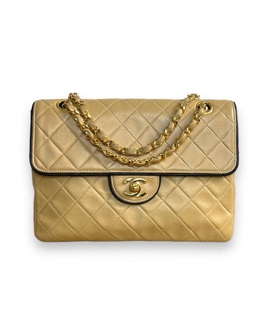 Chanel "Mademoiselle" en cuir matelassé beige gansé noir avec son fermoir siglé CC en métal doré sur rabat.